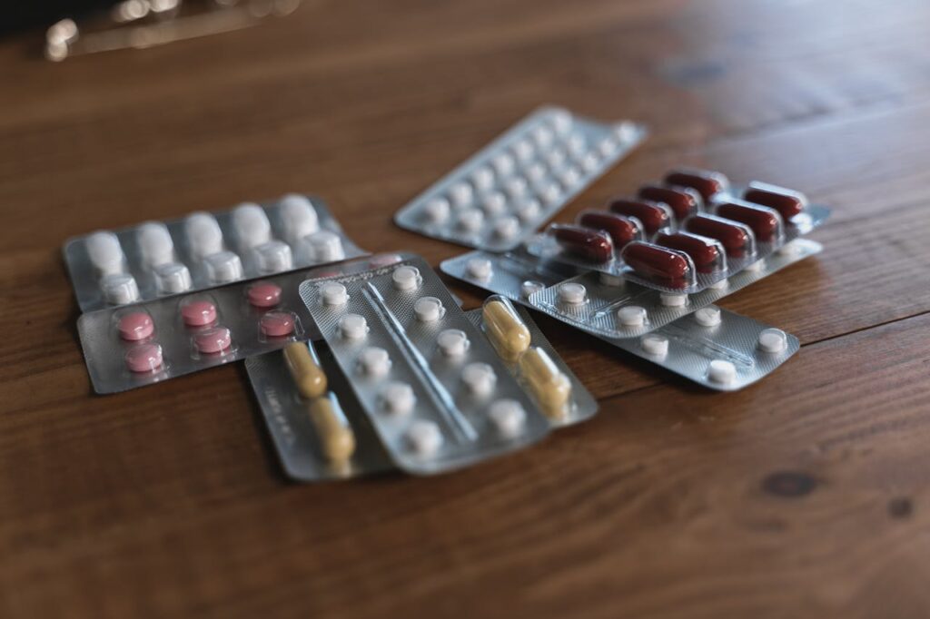 Assorted Packs of Pills on a Wooden Table